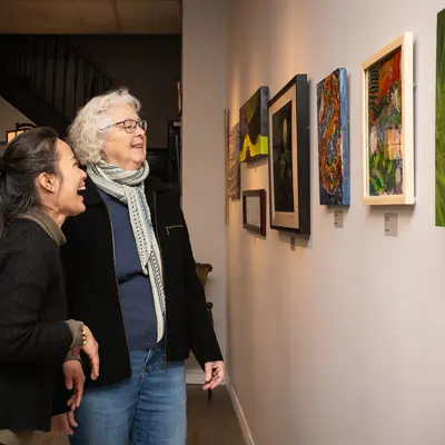 An art gallery owner and exhibit curator share a laugh while showing patrons a new exhibit celebrating the Year of the Snake.