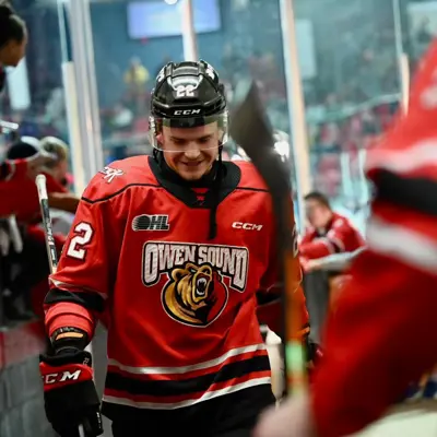 A hockey player for the Owen Sound Attack looks proud and happy while exiting the rink as the crowd cheers.