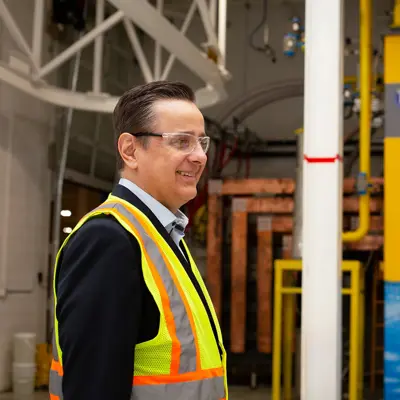A man in a suit and safety vest gives a tour of the facilities at Hydrogen Optimized.