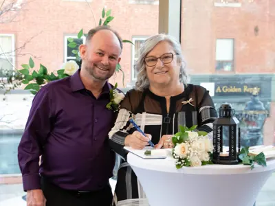 Man and woman signing paper on tall table