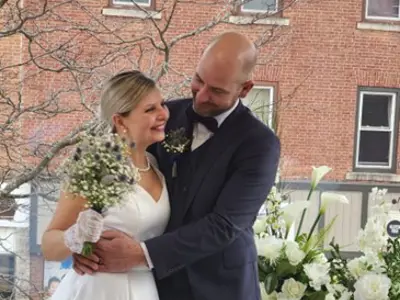 Bride and groom embracing in front of flowers